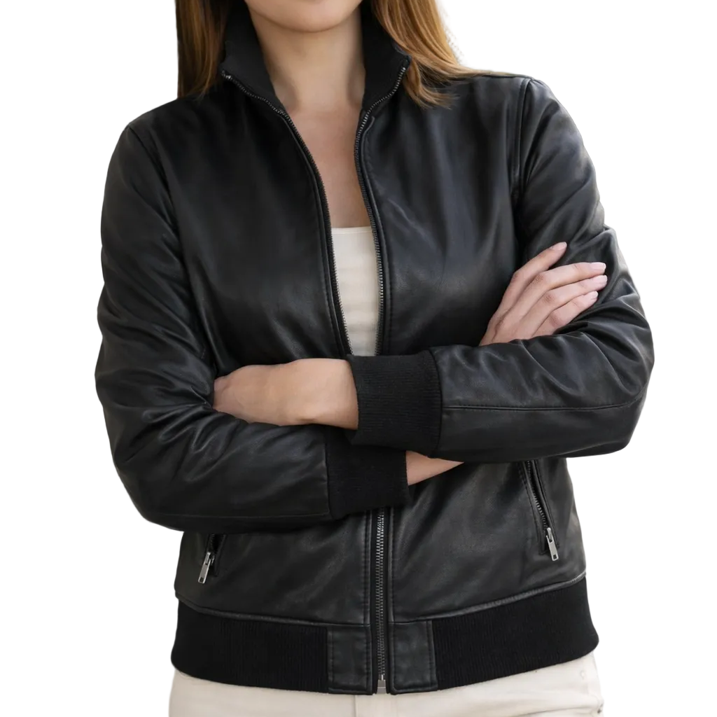 Woman wearing a black leather jacket standing against a wall.